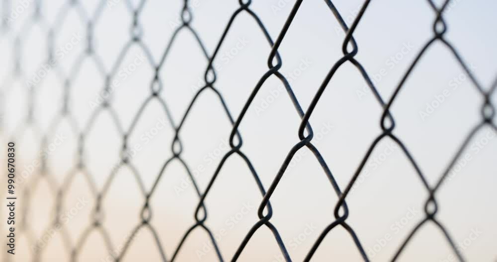 Fencing from a galvanized chain-link mesh on a gray background, close-up. Mesh fencing steel wire Fencing from a galvanized chain-link mesh on a gray background, close-up. Mesh fencing steel wire
