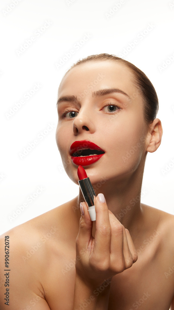 Portrait of young beautiful woman applying red lipstick, doing makeup isolated on white studio background. Concept of natural female beauty, skin care, cosmetics and cosmetology, products Portrait of young beautiful woman applying red lipstick, doing makeup isolated on white studio background. Concept of natural female beauty, skin care, cosmetics and cosmetology, products