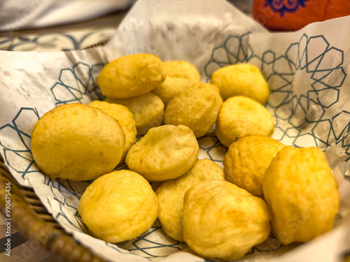 Baursaki is traditional pastry of national oriental cuisine. On a wooden plate, on a gray textured background