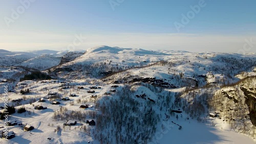 Aerial Drone Shot of Snow-Covered Winter Mountains and Cabins in Sinnes, Sirdal, Agder, Norway photo