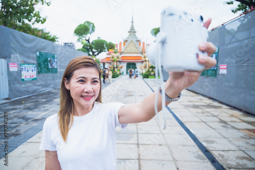 The group of South Asian tourists holding a map and searching for directions, with the iconic Wat Phra Kaew temple in the background in Bangkok, Thailand, enjoying their holiday adventure. photo