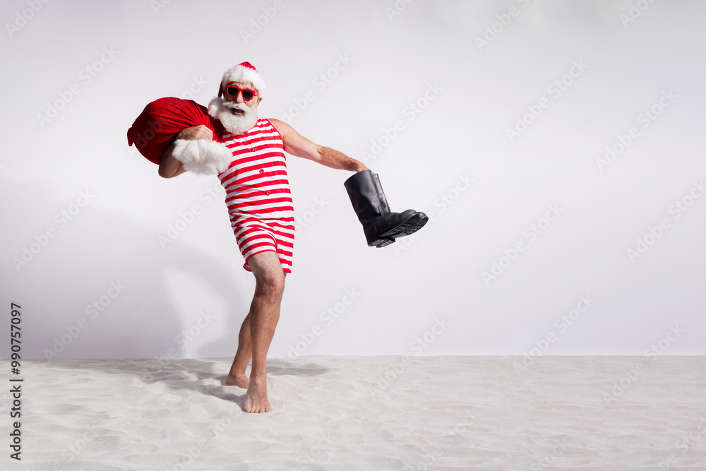 Obraz premium Photo of cheerful santa claus in red striped swimsuit sunglass vacation on island with white sandy beach