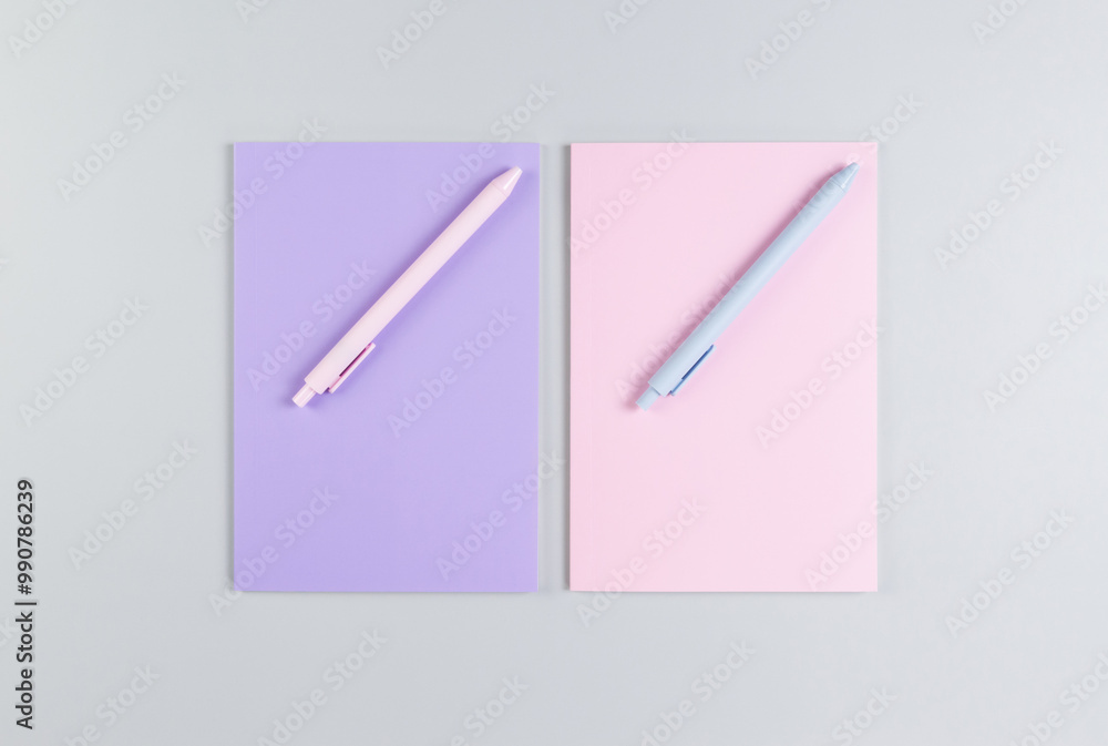 Top view of pink and purple notebooks, pink and blue pens on grey background. School, office wallpaper. Flat lay, copy space. Top view of pink and purple notebooks, pink and blue pens on grey background. School, office wallpaper. Flat lay, copy space.