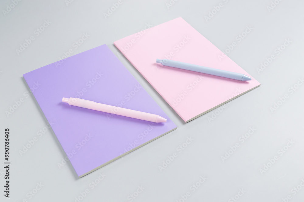 Top view of pink and purple notebooks, pink and blue pens on grey background. School, office wallpaper. Flat lay, copy space. Top view of pink and purple notebooks, pink and blue pens on grey background. School, office wallpaper. Flat lay, copy space.