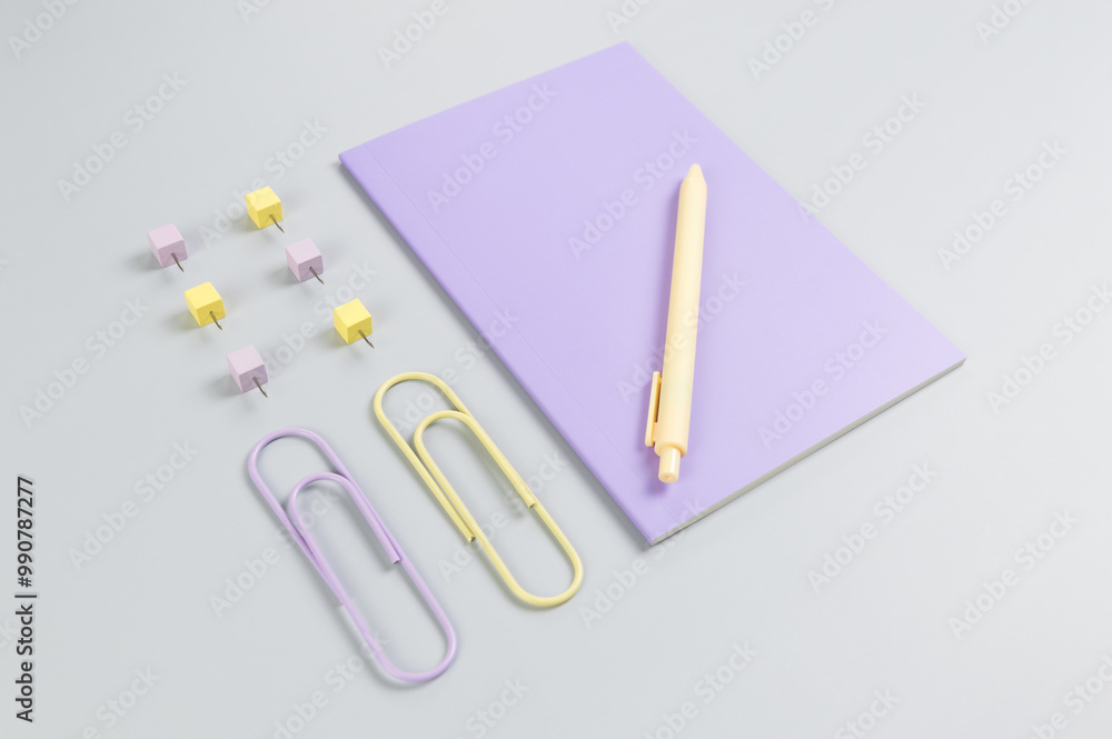 Top view of purple notebook on grey background. Paperclips, pen and pins. School, office wallpaper. Flat lay, copy space. Top view of purple notebook on grey background. Paperclips, pen and pins. School, office wallpaper. Flat lay, copy space.