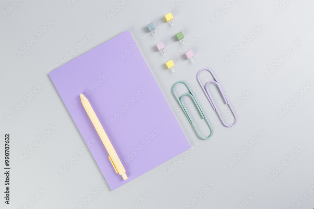 Top view of purple notebook on grey background. Paperclips, pen and pins. School, office wallpaper. Flat lay, copy space. Top view of purple notebook on grey background. Paperclips, pen and pins. School, office wallpaper. Flat lay, copy space.