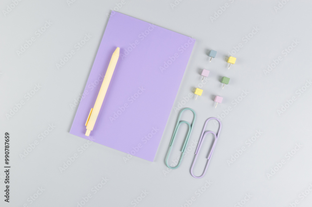 Top view of purple notebook on grey background. Paperclips, pen and pins. School, office wallpaper. Flat lay, copy space. Top view of purple notebook on grey background. Paperclips, pen and pins. School, office wallpaper. Flat lay, copy space.
