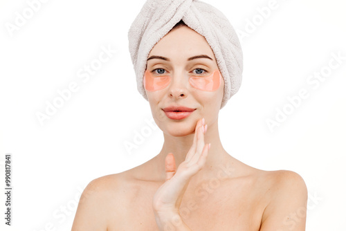 A young woman cares for her clean, makeup-free skin by applying moisturizing cream to her face. The white background highlights her dedication to skincare and her desire for a healthy appearance.