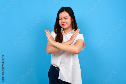 Stop. Concerned Asian woman showing refusal sign with crossed arms, saying no, raise awareness, standing and isoltaed on blue bright background, copyspace photo