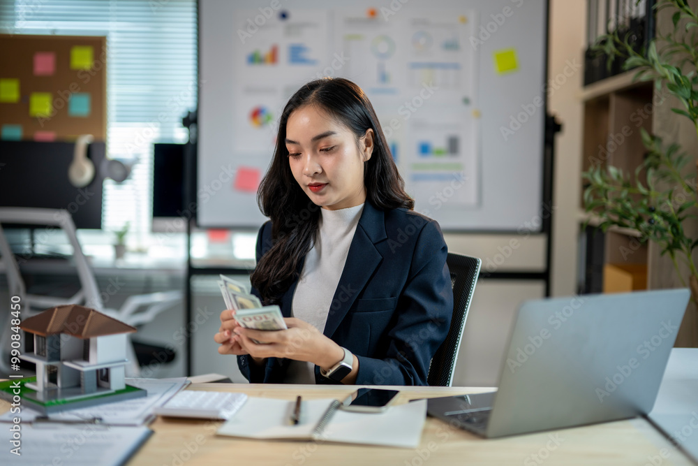 A woman in a business suit is looking at a stack of money A woman in a business suit is looking at a stack of money