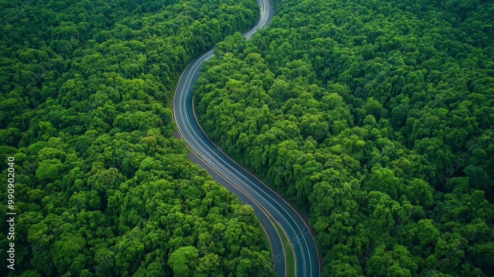 Aerial view of a winding highway through dense green forest, with no vehicles or people visible Aerial view of a winding highway through dense green forest, with no vehicles or people visible