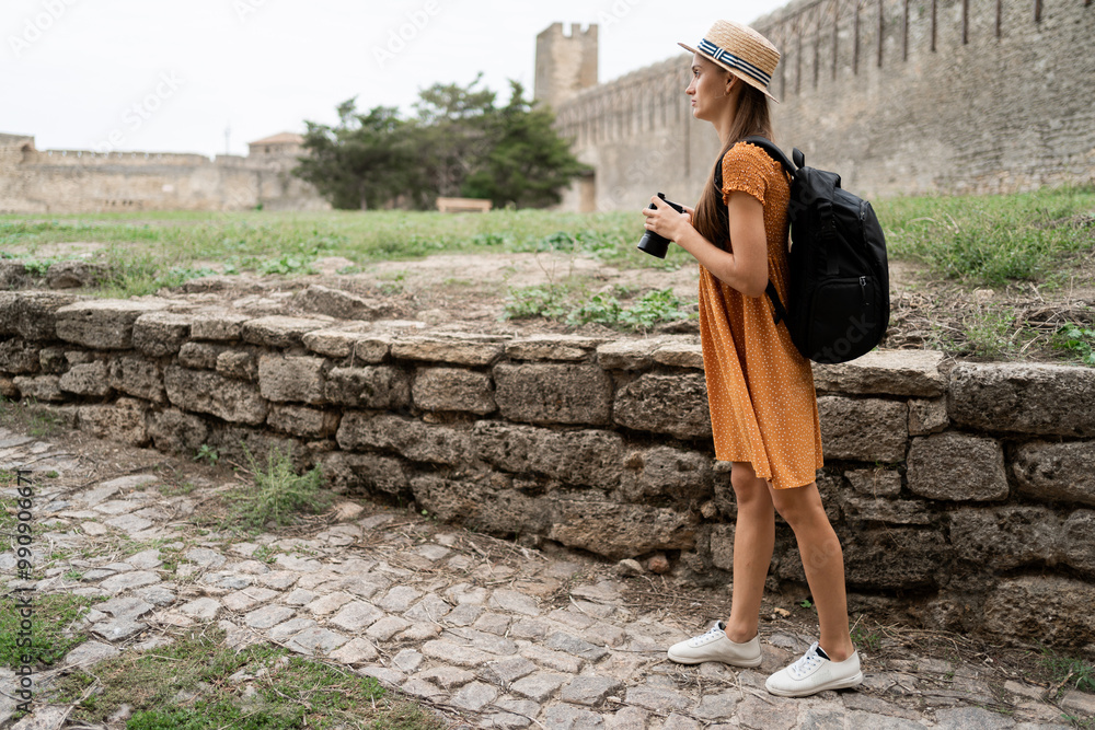 Fototapeta premium Woman exploring medieval castle with camera, photographing historic landmarks and capturing memories of her journey.