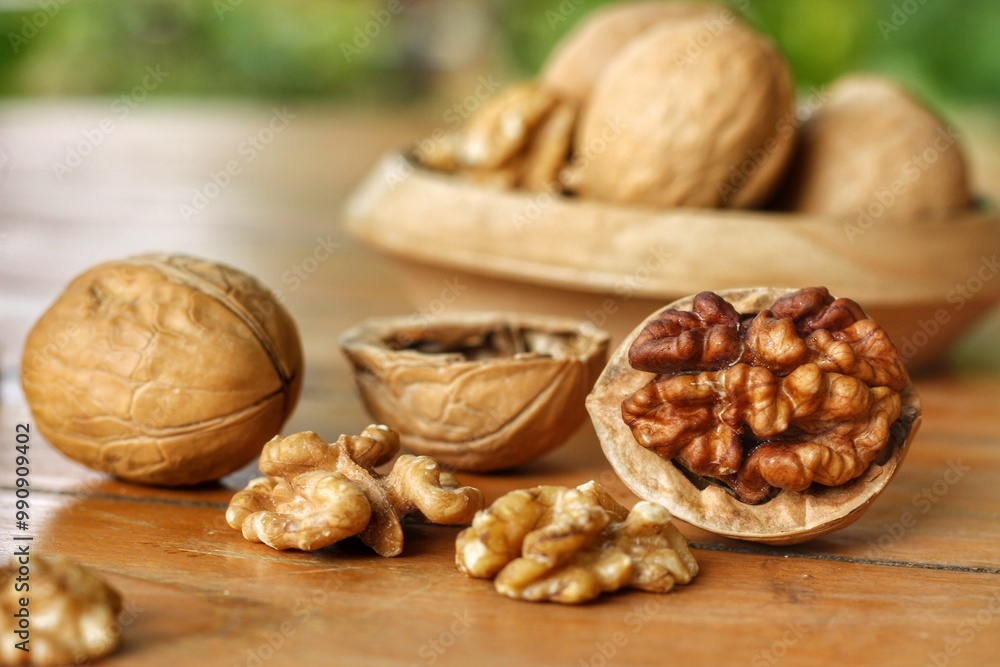 Cracked Walnut (Juglans regia) and whole seed in wooden bowl with blurred green background.Favorite for snack and very delicious.Have a lot of omega 3 for brain.Healthy food concept.Selective focus. Cracked Walnut (Juglans regia) and whole seed in wooden bowl with blurred green background.Favorite for snack and very delicious.Have a lot of omega 3 for brain.Healthy food concept.Selective focus.