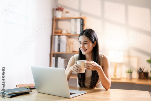 Young smiling beautiful asian businesswoman on coffee break in home office.