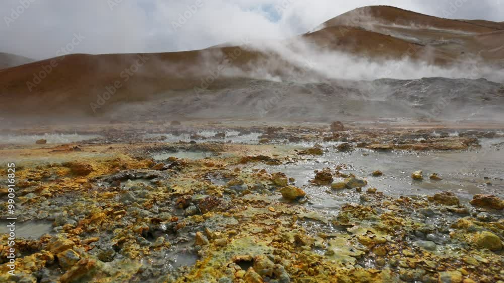 Geothermal area with hot springs gushing out from underground. Gimbal shot of red and grey soil with boiling water and steam. Geothermal energy
