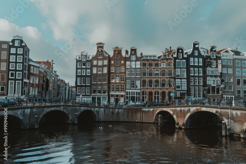 Canal reflecting traditional dutch houses under a cloudy sky in amsterdam, netherlands
