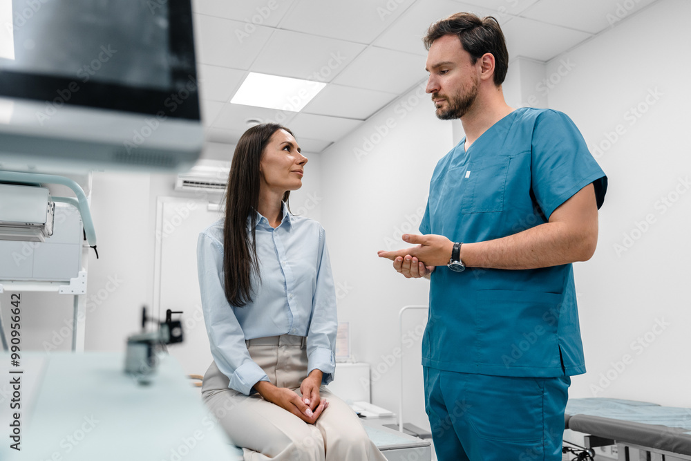 Obraz premium Serious Caucasian male doctor in blue medical uniform talk discuss results or symptoms with female patient after before X-ray computed tomography procedure in modern clinic hospital cabinet