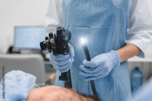 Gastrointestinal fiberoptic endoscopy concept. Cropped close up shot of female doctor holding modern endoscope device before gastroscopy examination with blue protective gloves