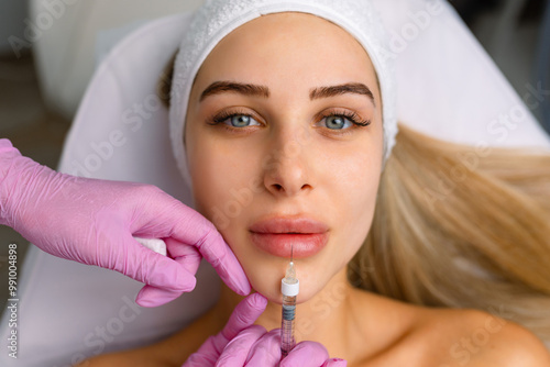 Injection procedure for lip augmentation, close-up. The cosmetologist slowly and carefully injects filler into the client lips. Advertising concept for facial care, youth and beauty