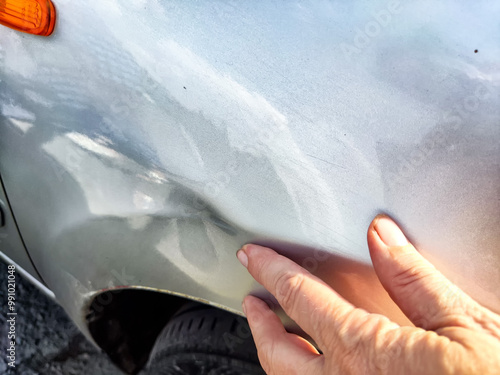 Fotografie A hand points to a dent on a silver car door
