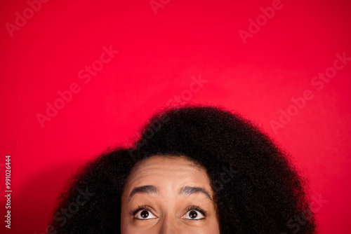 Cropped photo of adorable lovely girl celebrating noel xmas looking up empty space isolated red color background