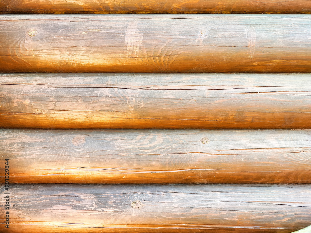 Horizontal wooden logs display natural grain patterns and warm tones in a rustic environment illuminated by daylight Horizontal wooden logs display natural grain patterns and warm tones in a rustic environment illuminated by daylight