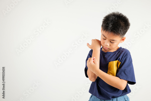 Asian little kid boy scratching itchy arm from a mosquito bite at studio shot isolated on white background, Portrait of Thai primary child dermatitis and scabies, Allergy symptoms, Malaria day concept