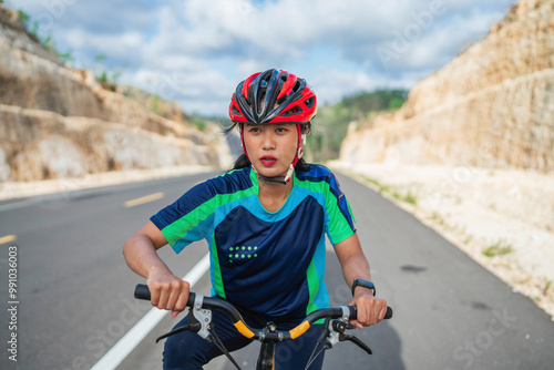 female biker biking with her hands on the handle bar, wearing helmet, biking concept photo