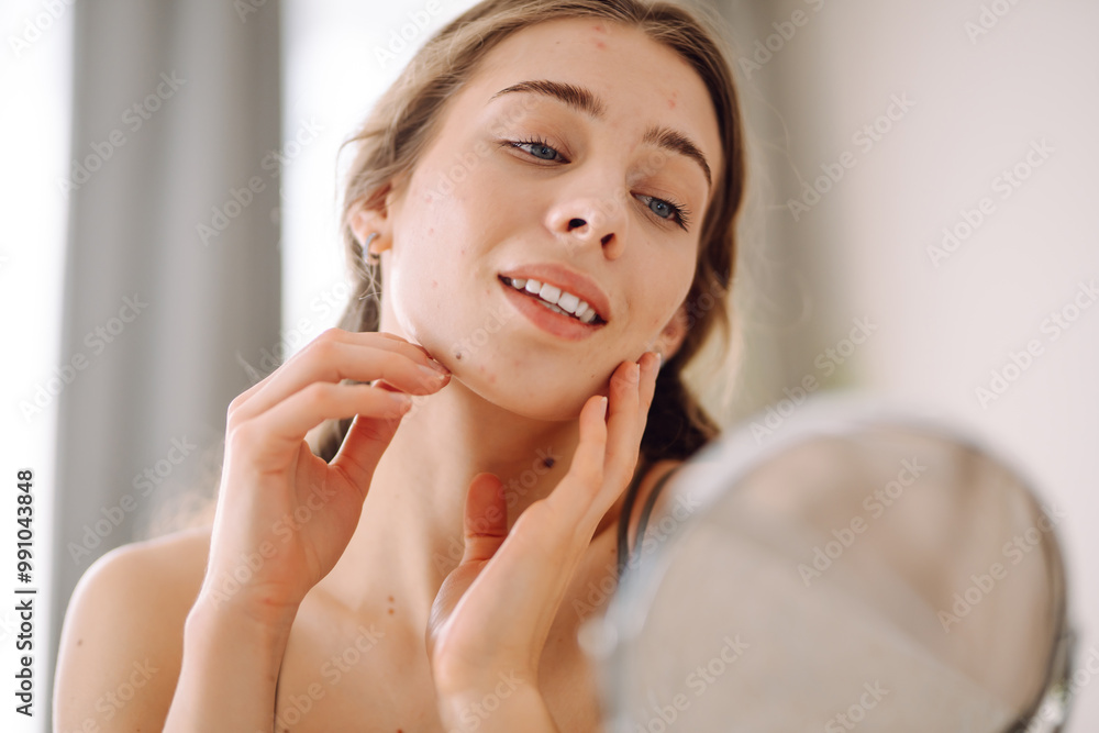 A young woman with problem skin is engaged in her skincare routine, gently touching her face while looking into a mirror in a well-lit, minimalist setting. Concept of acne therapy, scars, inflammation A young woman with problem skin is engaged in her skincare routine, gently touching her face while looking into a mirror in a well-lit, minimalist setting. Concept of acne therapy, scars, inflammation