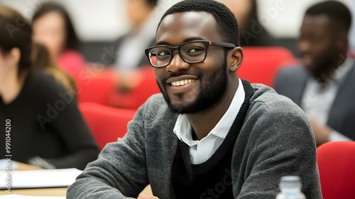 Smiling man wearing glasses in a classroom setting, engaged in learning. photo