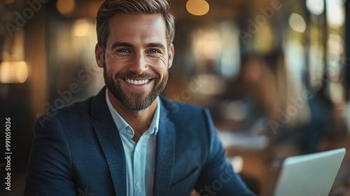 Young business professionals in blue, smiling and shaking hands, hold laptops in an office.