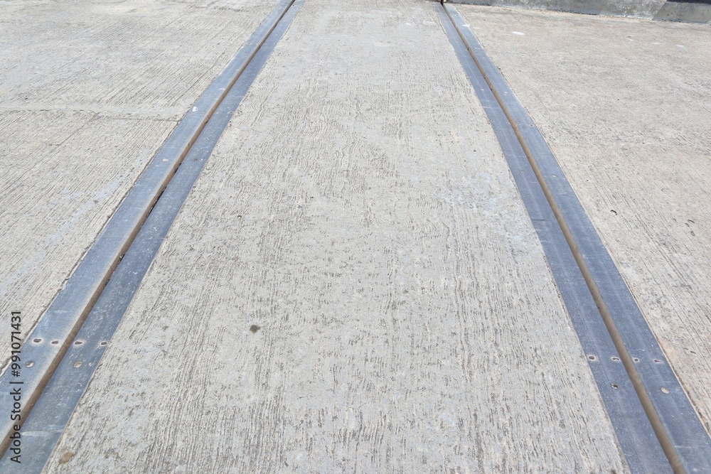 Fototapeta premium Industrial Concrete Surface with Metal Expansion Joints, A Close-Up Perspective