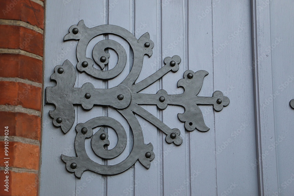 closeup of a beautiful antique metal ornament from the hinge on a blue wooden door closeup of a beautiful antique metal ornament from the hinge on a blue wooden door