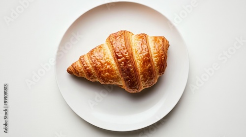 A buttered croissant with a crisp outer layer, positioned on a white plate against a minimal white background, highlighting its texture.