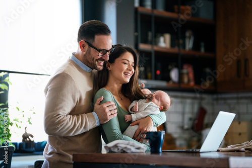 Cheerful young family with a baby child enjoying online purchasing on the internet at home