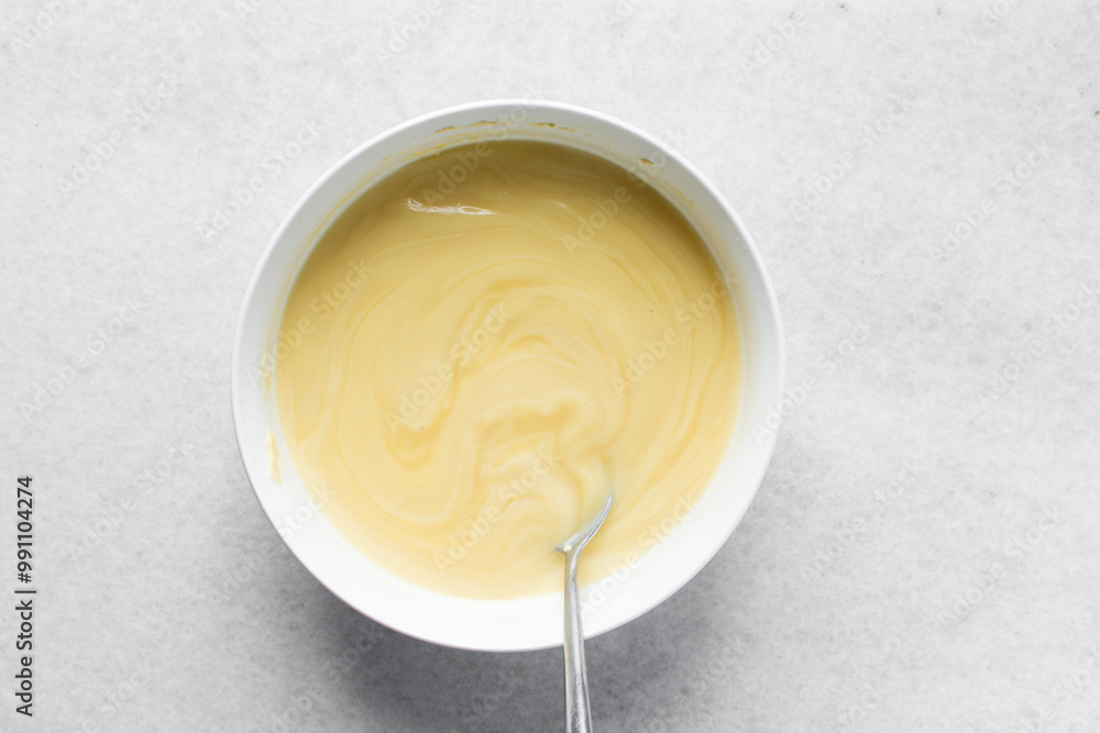Overhead view of nigerian akamu being made in a white bowl, pap akamu or ogi in a white bowl, top view of nigerian corn pudding in a white ramekin Overhead view of nigerian akamu being made in a white bowl, pap akamu or ogi in a white bowl, top view of nigerian corn pudding in a white ramekin