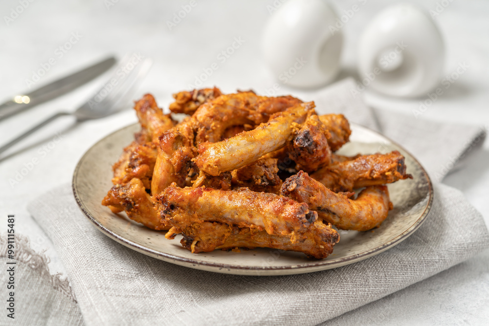 Baked chicken necks in a ceramic plate on a light culinary background closeup