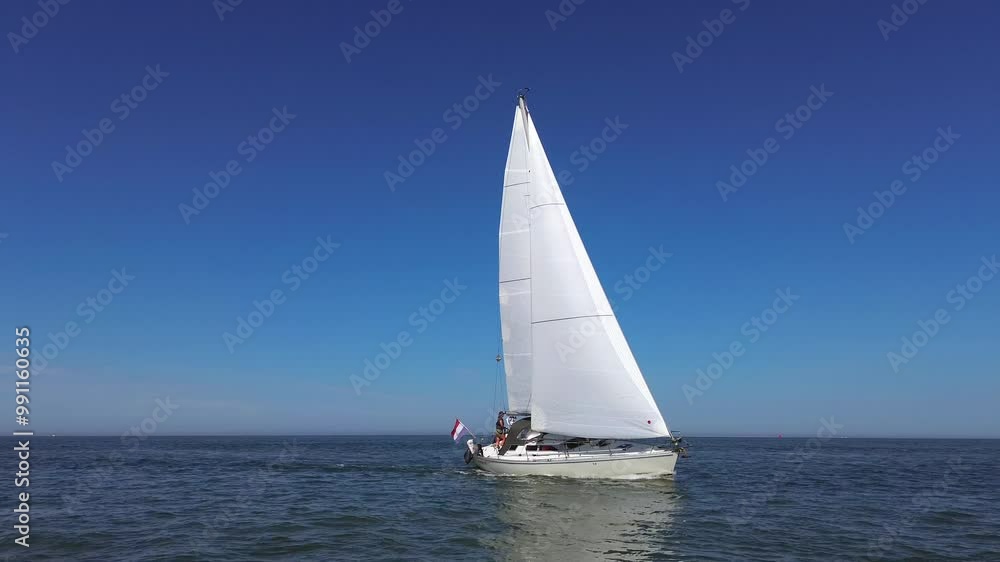 forward aerial drone 4K film of sailboat yacht sailing on sea ocean water with Dutch holland flag at sunder bright blue summer sky forward aerial drone 4K film of sailboat yacht sailing on sea ocean water with Dutch holland flag at sunder bright blue summer sky