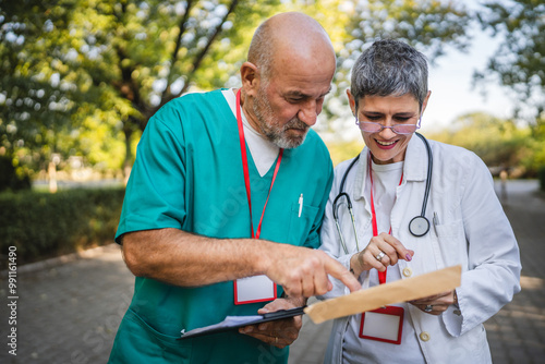 Healthcare professionals colleagues discuss patient records outdoors