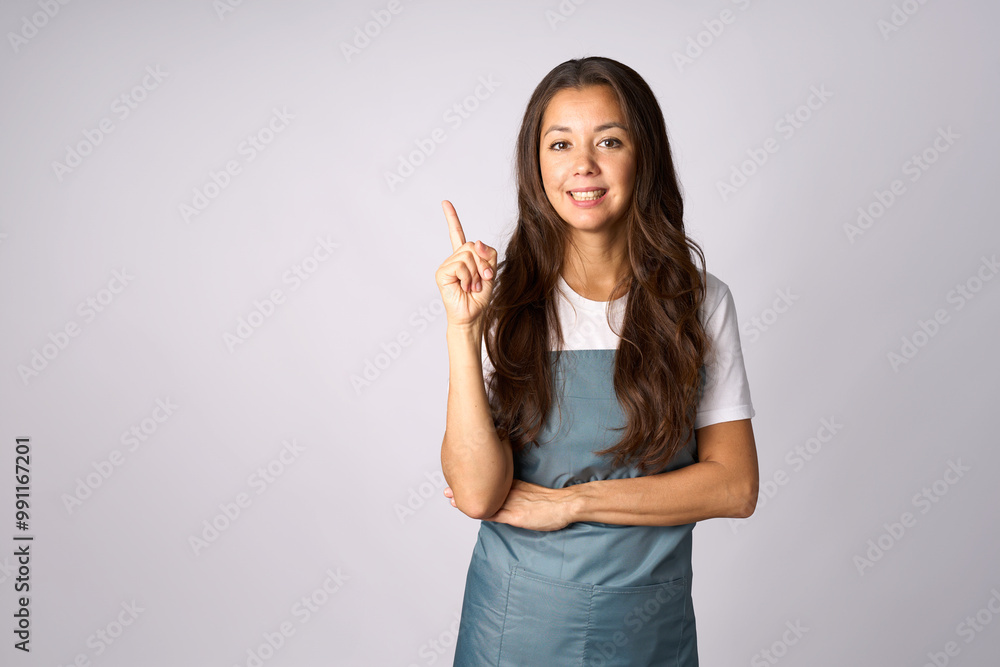 Happy woman in apron presenting product isolated on white background with copy space. Beautiful smiling woman wearing apron, pointing to empty space with finger Happy woman in apron presenting product isolated on white background with copy space. Beautiful smiling woman wearing apron, pointing to empty space with finger