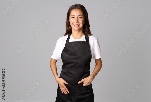 Friendly waitress, female barista in black apron. Young woman wearing black apron and white shirt standing on a white background with copy space