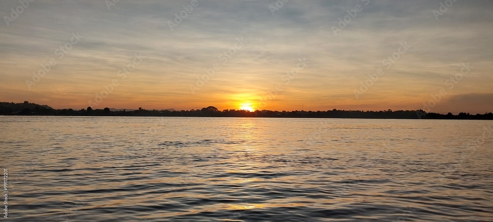 Fototapeta premium Stunning sunset over a calm lake with a mix of colorful skies and serene water, capturing the beauty of nature's evening display.