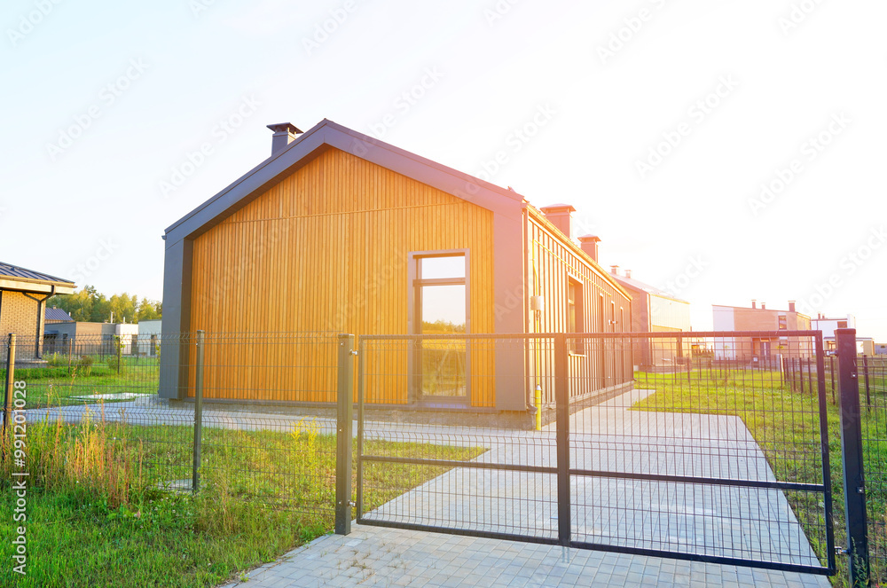 Obraz premium Barn House with green lawn. Barnhouse building in forest. Modern Family house on sunset. Cottage Scandi Barn home in suburb. Barndominium. Sustainable house in rural. Modern house with euro fence.