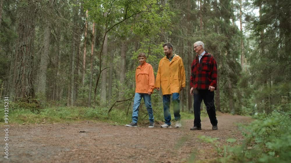 Grandfather, son and teenager grandson walk together along pathway in forest. Three male family generations enjoying bonding together, communication and strolling. Elderly and adult man, and teen boy Grandfather, son and teenager grandson walk together along pathway in forest. Three male family generations enjoying bonding together, communication and strolling. Elderly and adult man, and teen boy