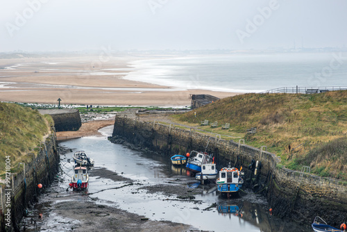 фотографія Tidal harbour in England with low mud port and small fishing vessel ships run ag
