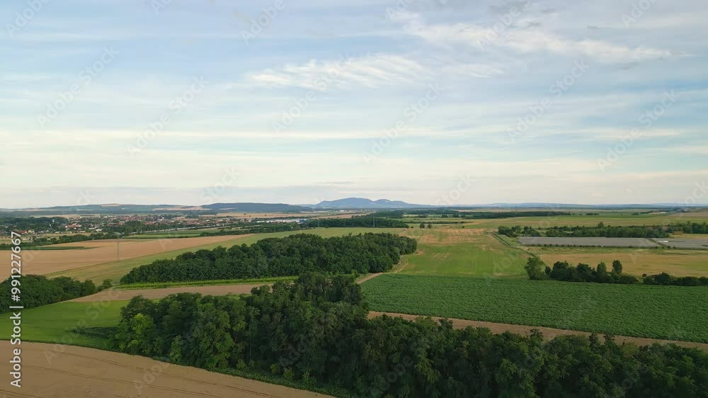 Aerial drone view of fields and small woodlands with the rolling hills of Pálava in the background. The elevated perspective showcases the harmonious blend of agriculture, nature, and the scenic count Aerial drone view of fields and small woodlands with the rolling hills of Pálava in the background. The elevated perspective showcases the harmonious blend of agriculture, nature, and the scenic count