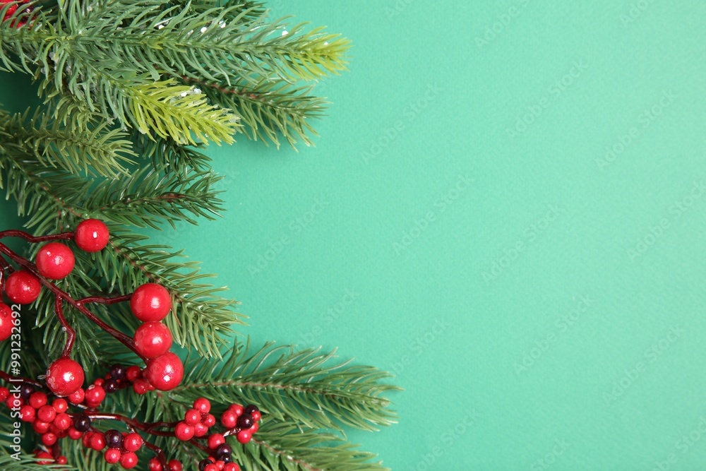 Christmas decor. Fir tree branches and red berries on turquoise background, flat lay. Space for text Christmas decor. Fir tree branches and red berries on turquoise background, flat lay. Space for text
