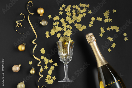 Flat lay composition with Christmas balls, confetti and bottle of sparkling wine on black background