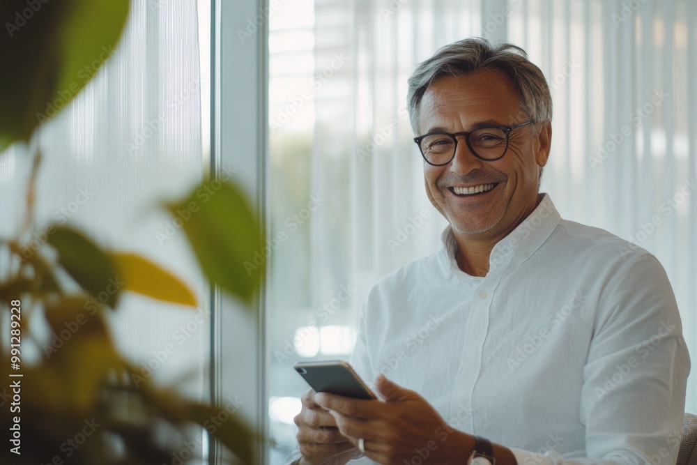 Senior man smiling with smartphone in relaxed office environment Senior man smiling with smartphone in relaxed office environment