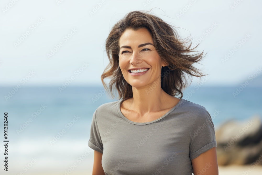 Portrait of a satisfied woman in her 40s dressed in a casual t-shirt in front of serene seaside background Portrait of a satisfied woman in her 40s dressed in a casual t-shirt in front of serene seaside background